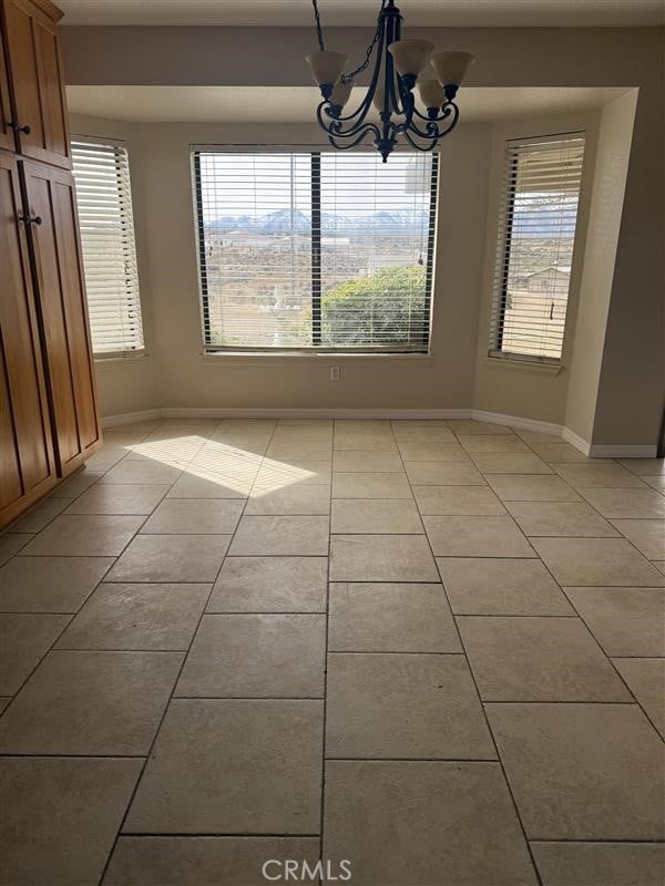 unfurnished dining area featuring a wealth of natural light, a notable chandelier, and light tile patterned floors