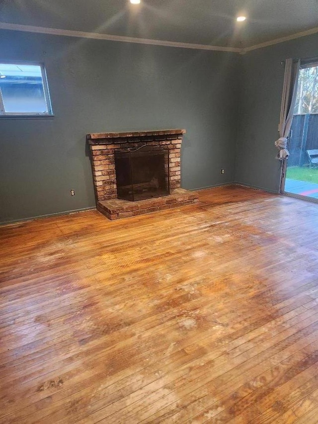 unfurnished living room featuring ornamental molding, a brick fireplace, and light hardwood / wood-style floors