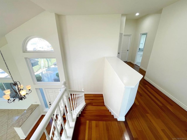 staircase with wood-type flooring, a chandelier, and a high ceiling