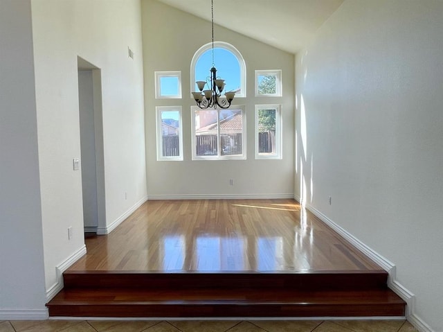 interior space featuring light tile patterned floors, a notable chandelier, and high vaulted ceiling