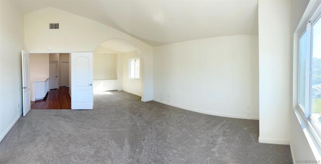 unfurnished room featuring vaulted ceiling and dark colored carpet