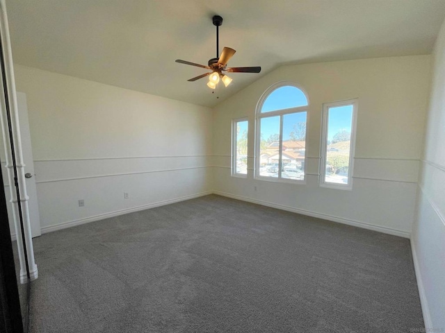 empty room with ceiling fan, vaulted ceiling, and dark colored carpet