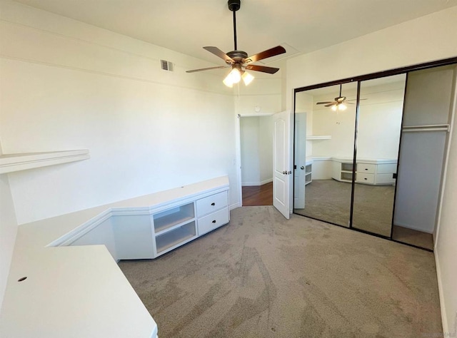 unfurnished bedroom with light colored carpet, ceiling fan, and a closet