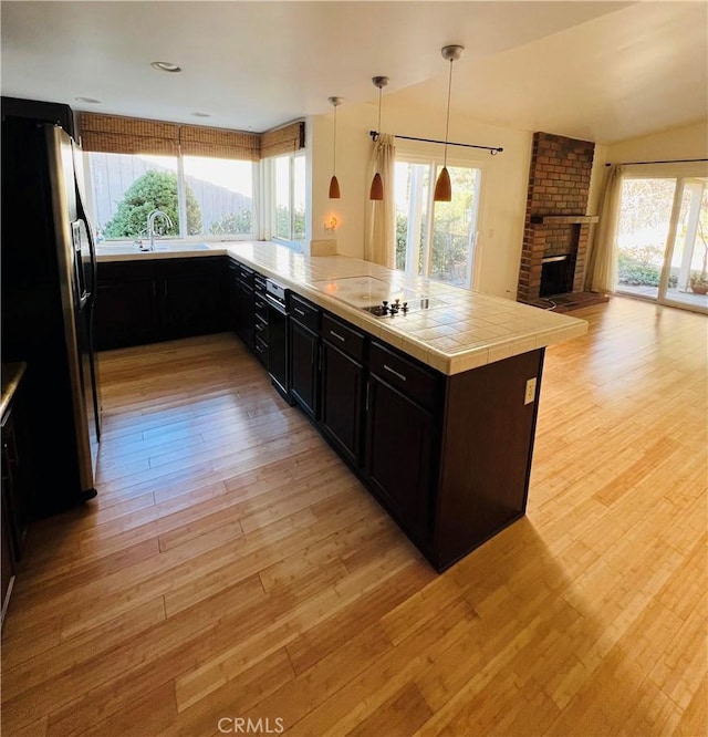 kitchen with pendant lighting, stainless steel fridge with ice dispenser, kitchen peninsula, and a healthy amount of sunlight