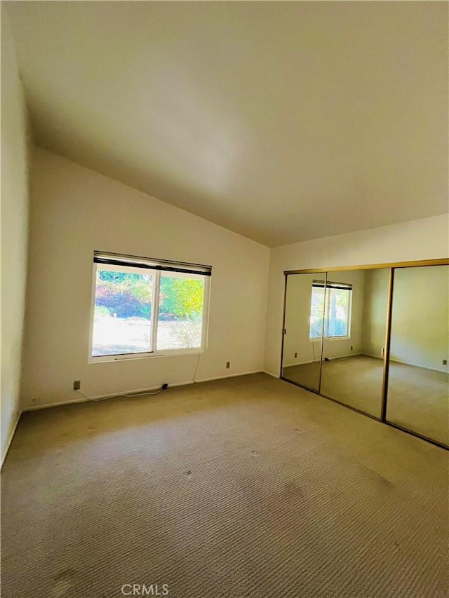 unfurnished bedroom featuring carpet floors, vaulted ceiling, and a closet