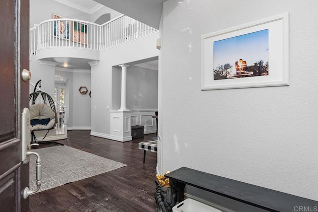 entrance foyer featuring crown molding, dark hardwood / wood-style floors, and ornate columns