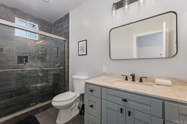 bathroom featuring vanity, toilet, and a shower with door