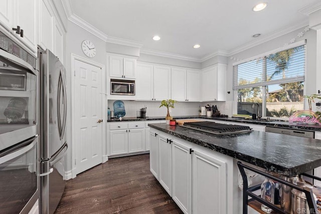 kitchen featuring appliances with stainless steel finishes, white cabinetry, dark hardwood / wood-style flooring, decorative backsplash, and dark stone counters