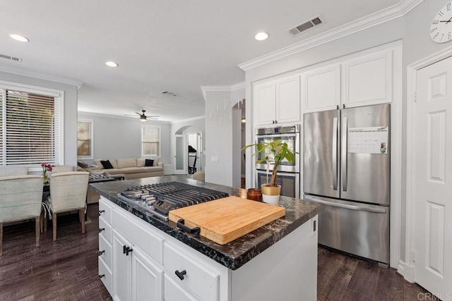 kitchen featuring stainless steel appliances, crown molding, a center island, and white cabinets