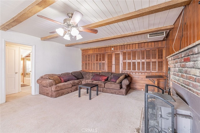 carpeted living room with ceiling fan, wooden ceiling, beam ceiling, and wood walls