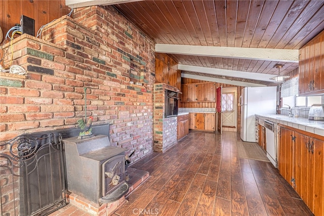 kitchen with beamed ceiling, a wood stove, oven, white dishwasher, and wood ceiling