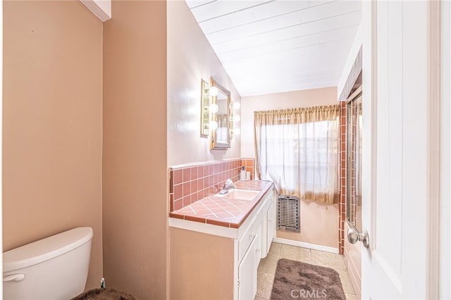 bathroom featuring lofted ceiling, toilet, tasteful backsplash, vanity, and tile patterned flooring