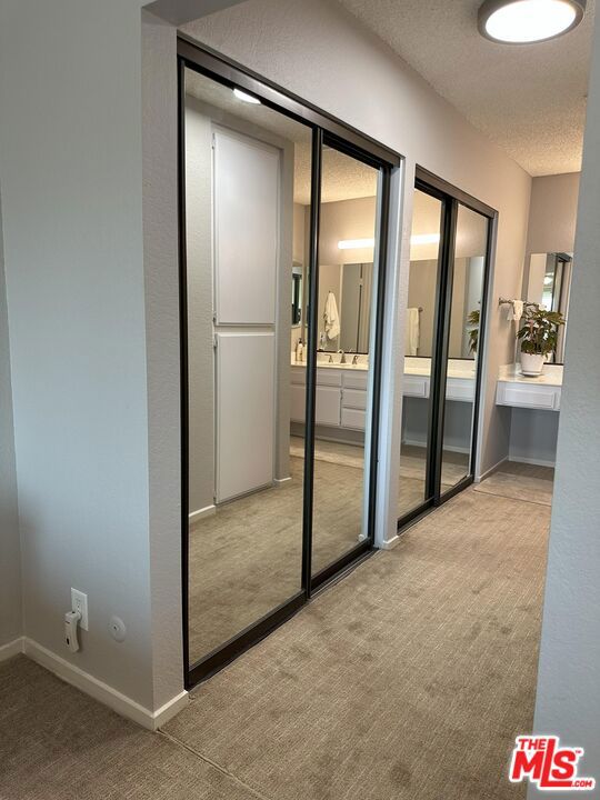 doorway to outside with light colored carpet and a textured ceiling