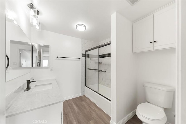 full bathroom with hardwood / wood-style flooring, enclosed tub / shower combo, vanity, and toilet