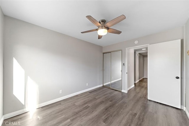 unfurnished bedroom with dark hardwood / wood-style flooring, a closet, and ceiling fan