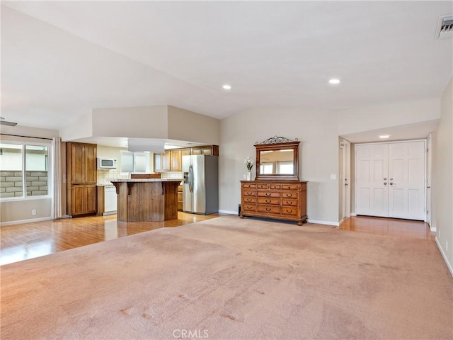 unfurnished living room featuring light colored carpet and vaulted ceiling