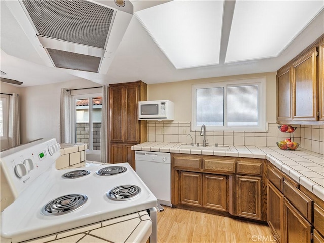 kitchen with white appliances, tile countertops, sink, and a wealth of natural light