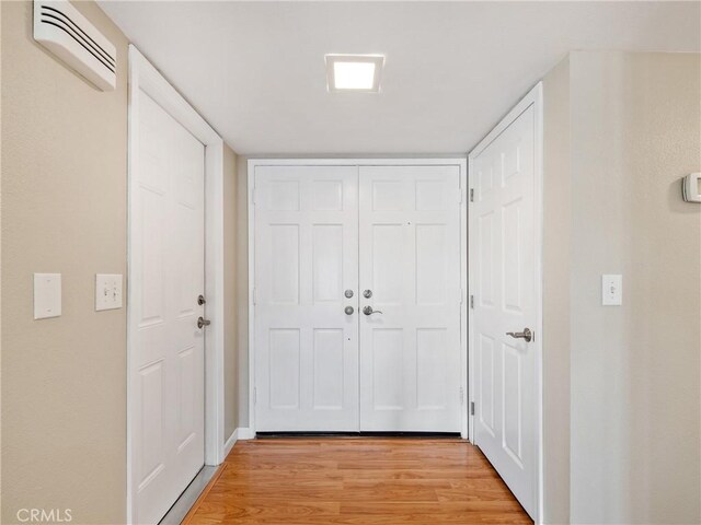 hallway with a wall mounted air conditioner and light hardwood / wood-style floors