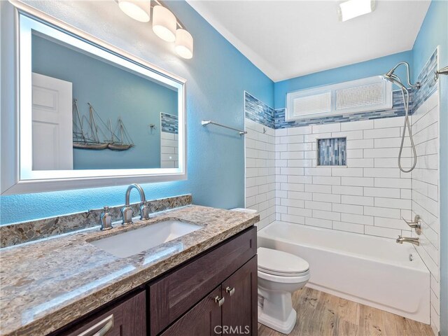 full bathroom featuring tiled shower / bath combo, vanity, hardwood / wood-style floors, and toilet