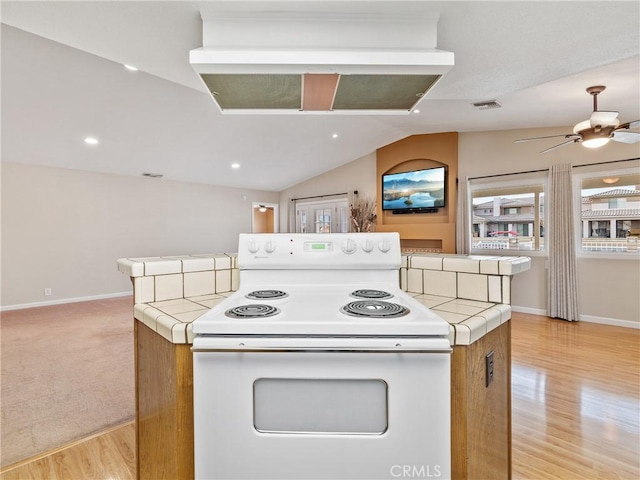 kitchen with light wood-type flooring, electric range, tile counters, and vaulted ceiling