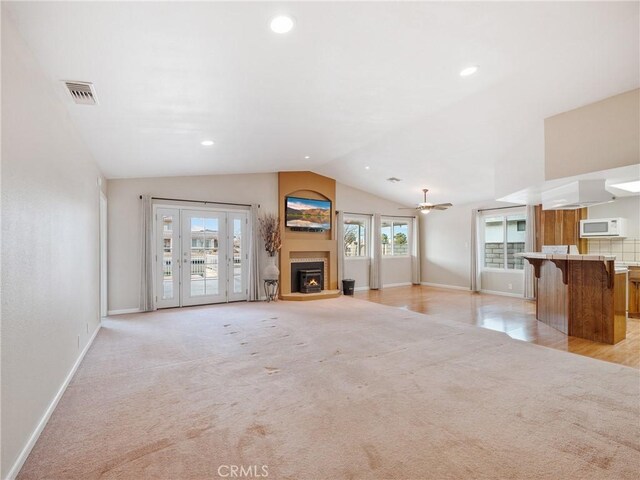 unfurnished living room with ceiling fan, light colored carpet, and vaulted ceiling