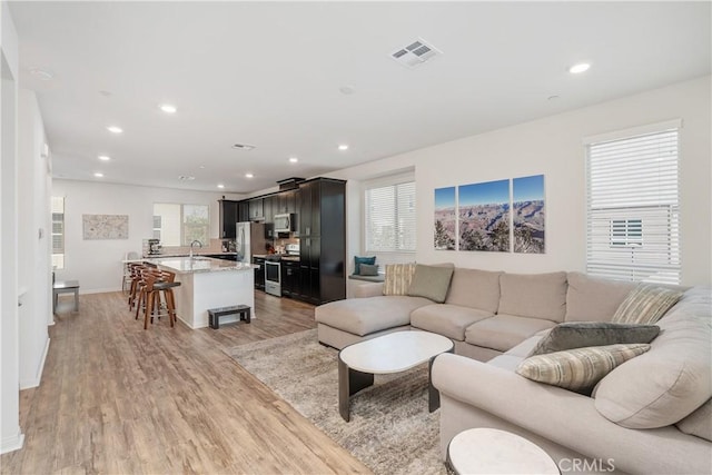 living room featuring sink and light hardwood / wood-style flooring