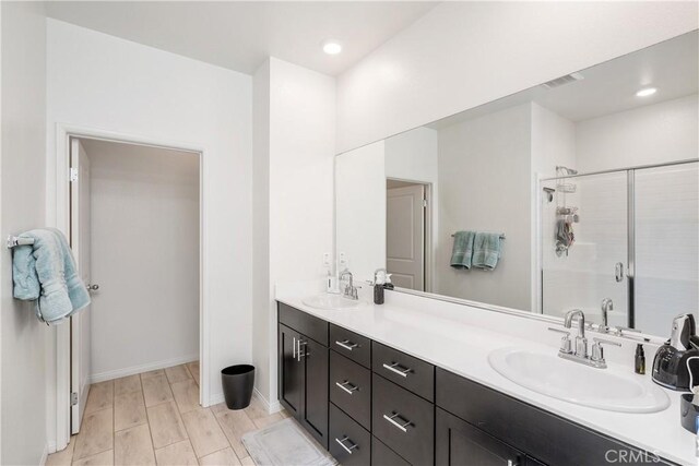 bathroom with an enclosed shower, vanity, and wood-type flooring