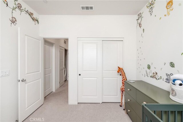 bedroom featuring light colored carpet and a closet