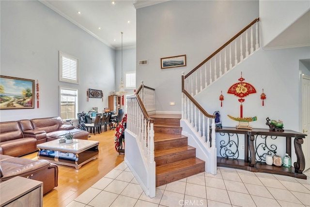 staircase with a high ceiling, ornamental molding, and tile patterned floors