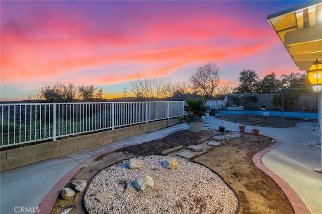 pool at dusk featuring a patio