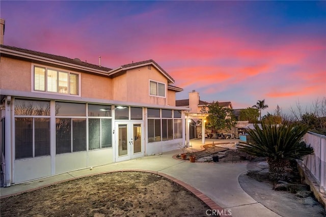 back house at dusk featuring a patio and french doors