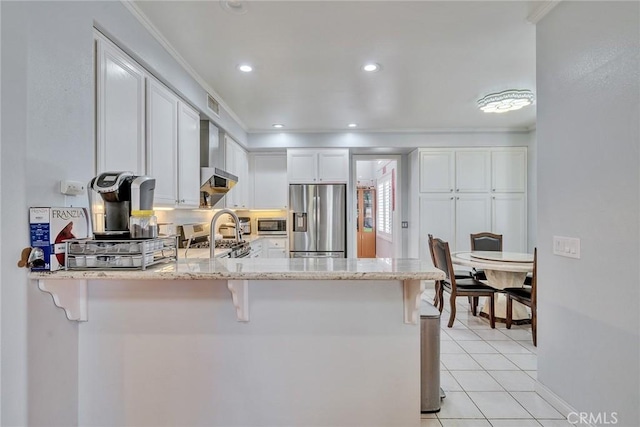 kitchen featuring a breakfast bar, white cabinetry, kitchen peninsula, stainless steel appliances, and light stone countertops