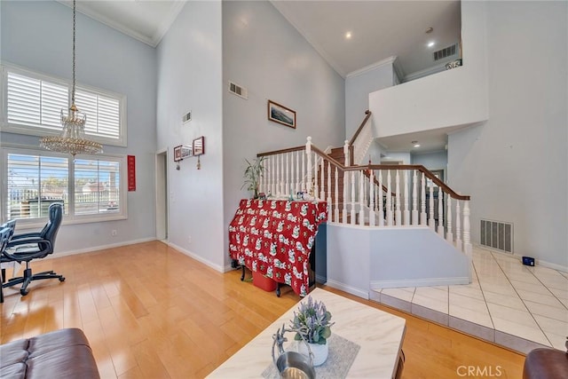 interior space with an inviting chandelier, wood-type flooring, ornamental molding, and a high ceiling