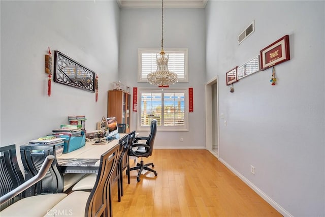 office featuring crown molding, light wood-type flooring, and a high ceiling