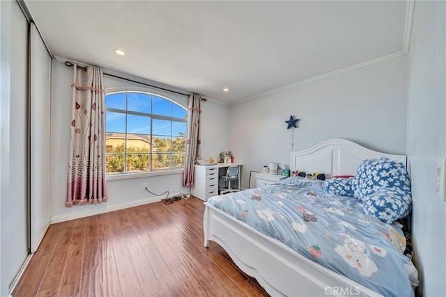 bedroom featuring crown molding, hardwood / wood-style flooring, and a closet