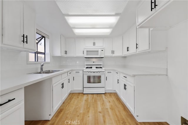 kitchen with sink, white appliances, backsplash, white cabinets, and light wood-type flooring