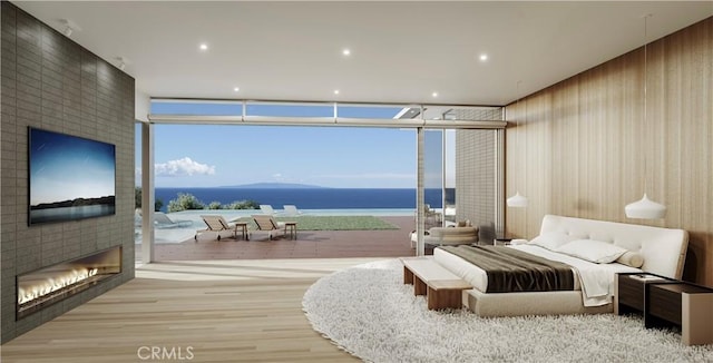 bedroom featuring a water view, light wood-type flooring, access to exterior, and a fireplace