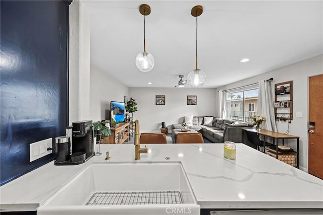 kitchen featuring hanging light fixtures, sink, and light stone counters