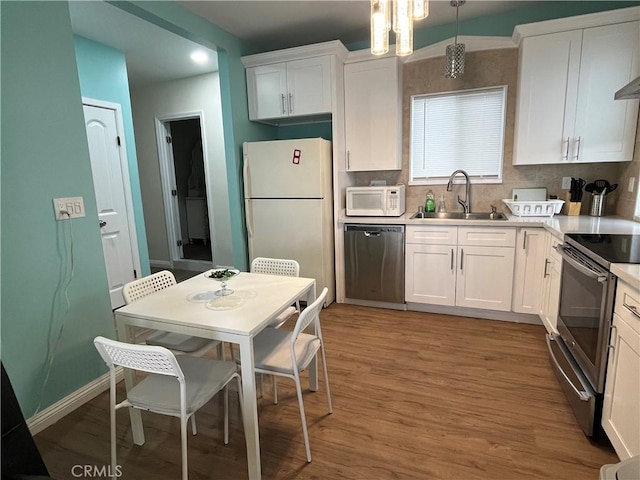 kitchen featuring white cabinetry, appliances with stainless steel finishes, sink, and decorative light fixtures