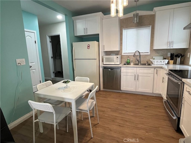 kitchen with white cabinetry, sink, decorative light fixtures, and appliances with stainless steel finishes