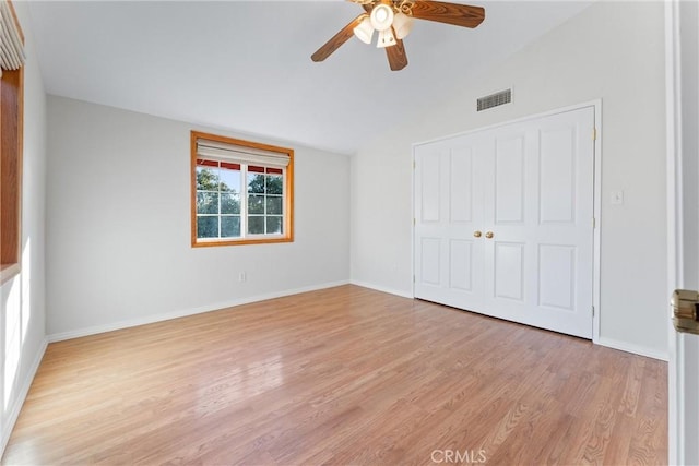 unfurnished bedroom with lofted ceiling, light wood-type flooring, ceiling fan, and a closet