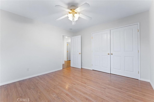 unfurnished bedroom featuring ceiling fan, a closet, and light wood-type flooring