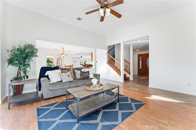 living room with ceiling fan with notable chandelier and hardwood / wood-style floors