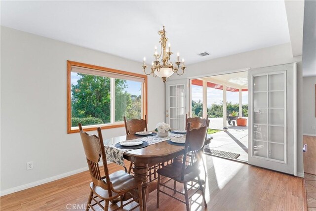 dining space featuring french doors, a notable chandelier, and light hardwood / wood-style flooring