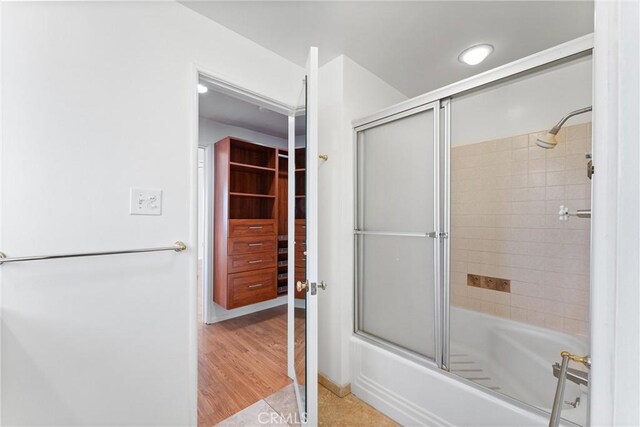 bathroom with hardwood / wood-style floors and bath / shower combo with glass door