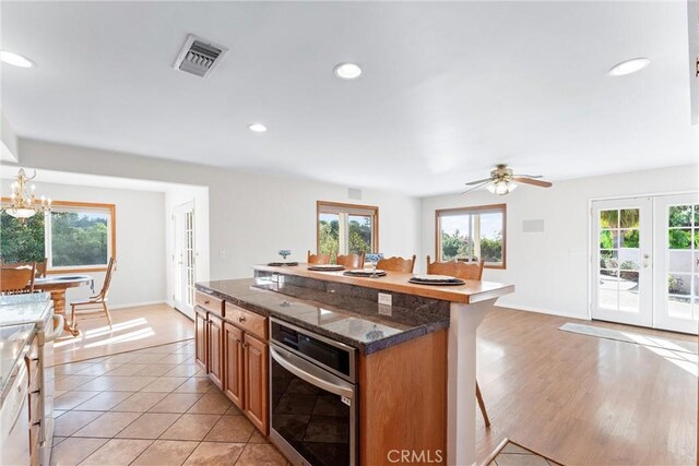 kitchen with a breakfast bar, an inviting chandelier, a kitchen island, french doors, and stainless steel oven