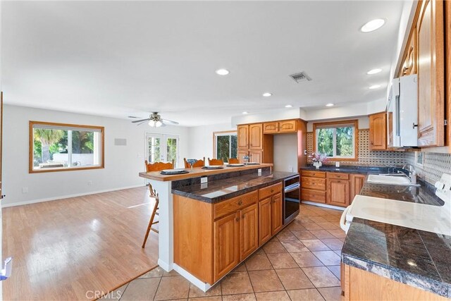 kitchen with tasteful backsplash, stainless steel oven, a breakfast bar area, and light tile patterned floors