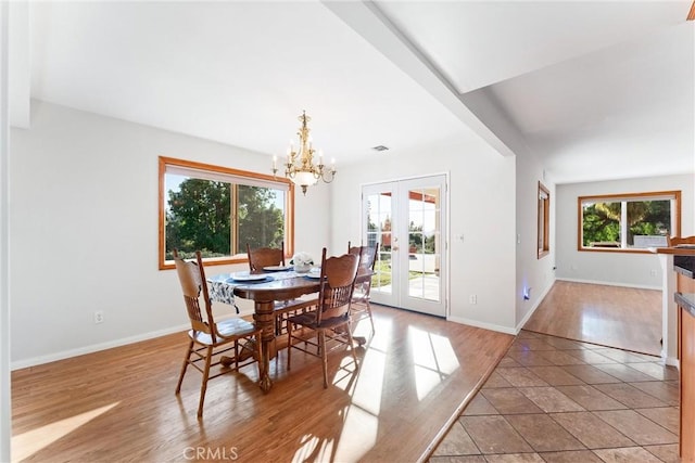 tiled dining area featuring plenty of natural light, a notable chandelier, and french doors