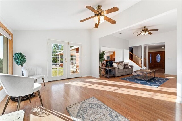 living room with lofted ceiling, light hardwood / wood-style flooring, and french doors