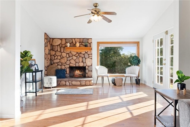 interior space featuring a stone fireplace, hardwood / wood-style floors, lofted ceiling, and ceiling fan